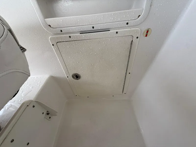 Slide: The Image of 2013 Robalo R245 Walkaround boat storage compartment with white interior and secure latch. - 32