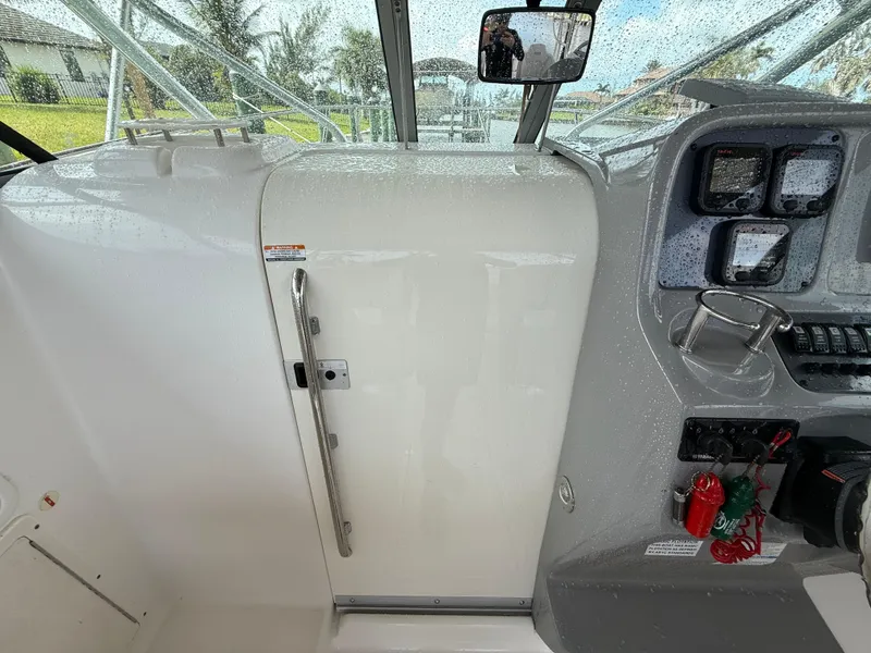 Slide: The Image of 2013 Robalo R245 Walkaround boat interior with control panel and cabin door. - 36