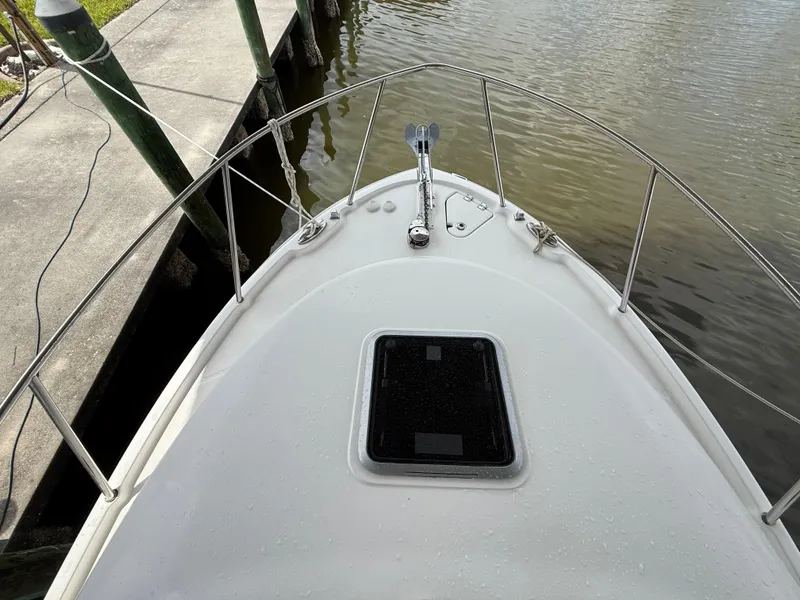 Slide: The Image of 2013 Robalo R245 Walkaround boat bow with railing and hatch, docked by calm water. - 45