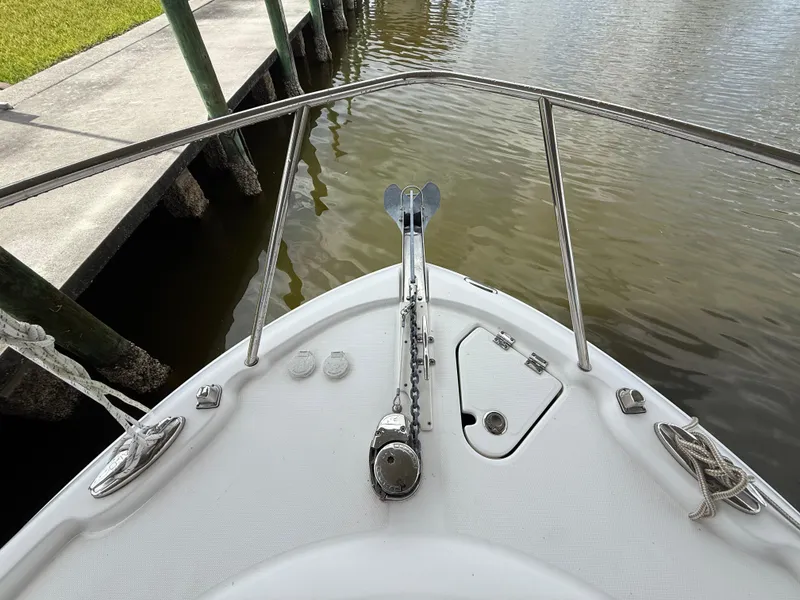 Slide: The Image of 2013 Robalo R245 Walkaround boat bow with anchor, docked by calm water. - 47