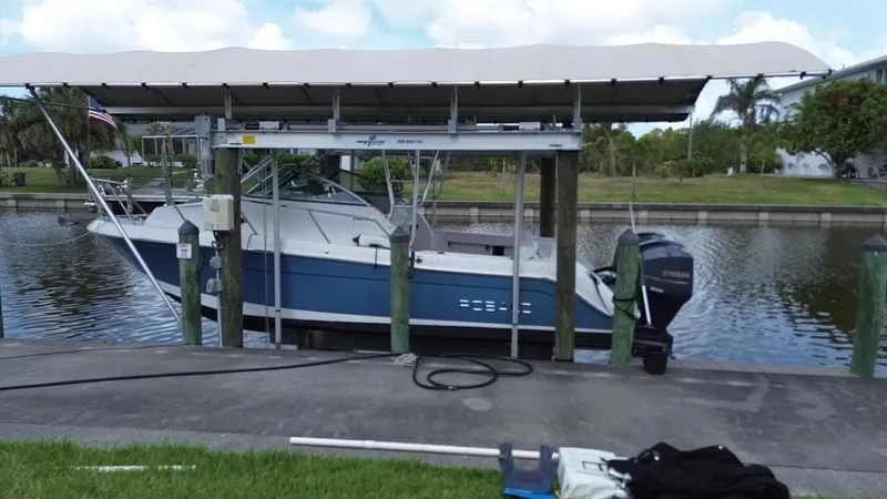 Slide: The Image of 2013 Robalo R245 Walkaround boat docked under a canopy on a calm canal. - 6