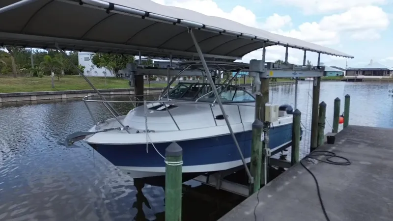 Slide: The Image of 2013 Robalo R245 Walkaround boat docked under a canopy on a lift. - 7