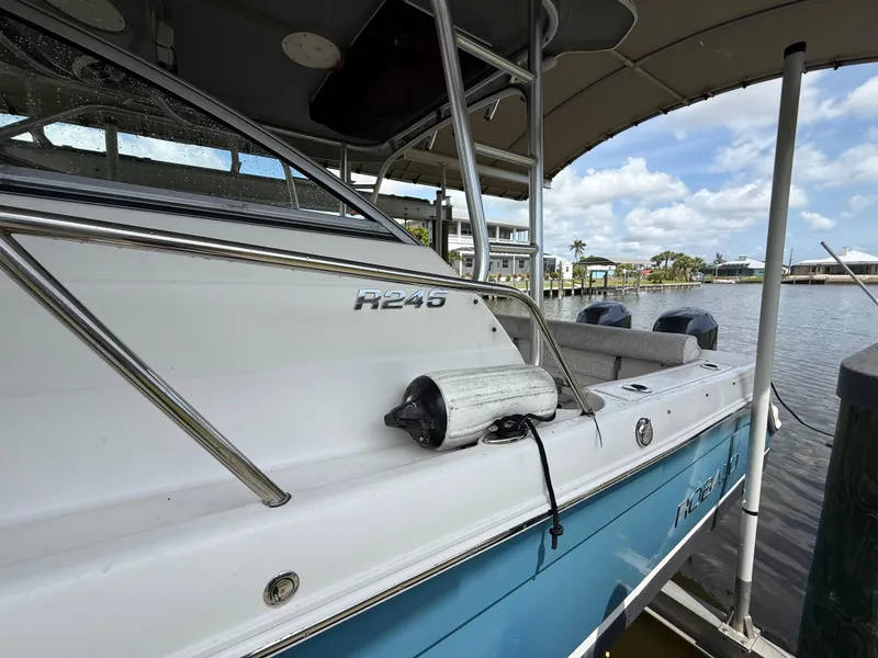 Slide: The Image of 2013 Robalo R245 Walkaround boat docked by the water under a cloudy sky. - 9