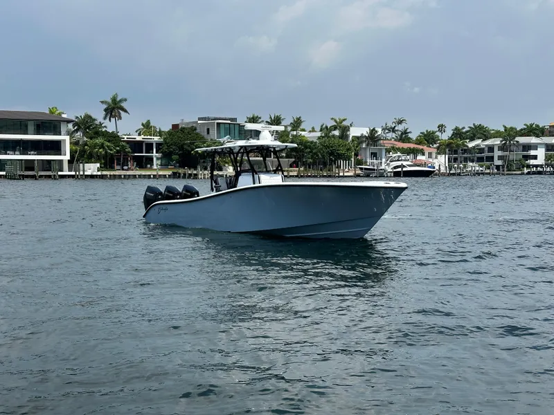 Slide: The Image of 2024 Yellowfin 34 Offshore boat cruising on a calm waterfront with modern homes in the background. - 2