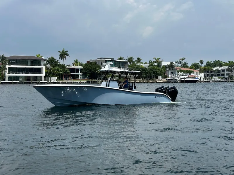 Slide: The Image of 2024 Yellowfin 34 Offshore boat cruising on a calm waterfront with luxury homes in the background. - 4
