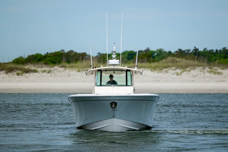 Slide: The Image of 2011 Grady-White Canyon 366 boat cruising near a sandy shoreline. - 2