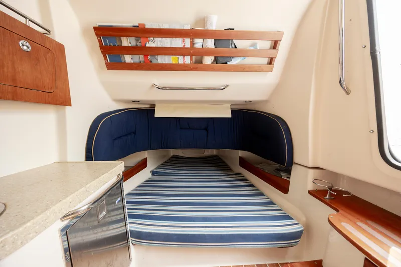 Slide: The Image of 2011 Grady-White Canyon 366 cabin interior with striped bedding and wooden storage shelves. - 26