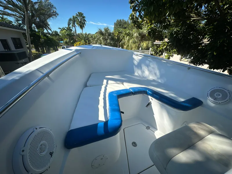 Slide: The Image of 2005 Sailfish 2360 CC boat with white and blue seating, surrounded by lush greenery. - 13