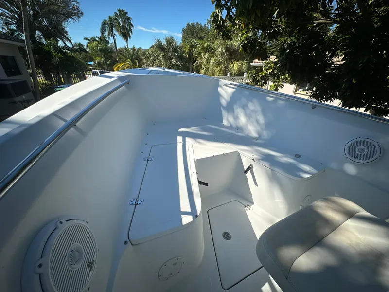 Slide: The Image of 2005 Sailfish 2360 CC boat interior with seating, speakers, and lush greenery in the background. - 14