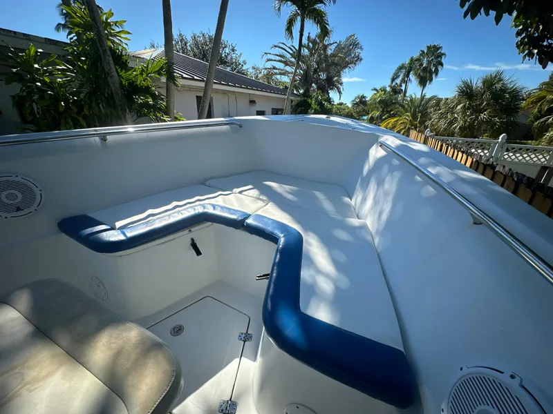 Slide: The Image of 2005 Sailfish 2360 CC boat interior with blue and white seating, surrounded by tropical trees. - 15