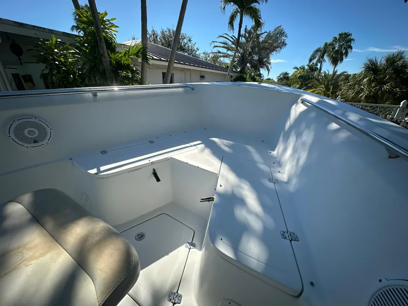 Slide: The Image of 2005 Sailfish 2360 CC boat interior with seating and storage, surrounded by tropical trees. - 16