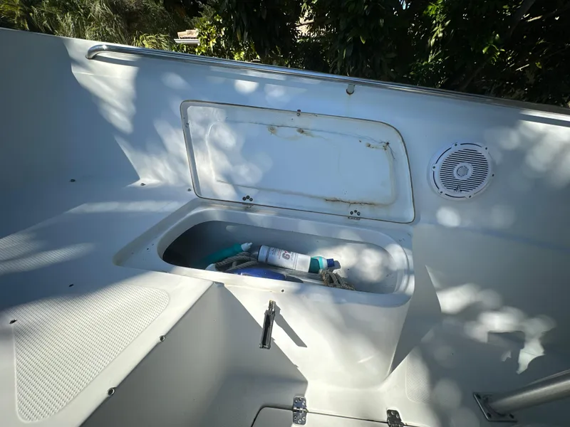 Slide: The Image of 2005 Sailfish 2360 CC boat storage compartment with open lid and visible contents. - 18