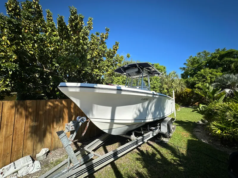 Slide: The Image of 2005 Sailfish 2360 CC boat on trailer, surrounded by lush greenery. - 2