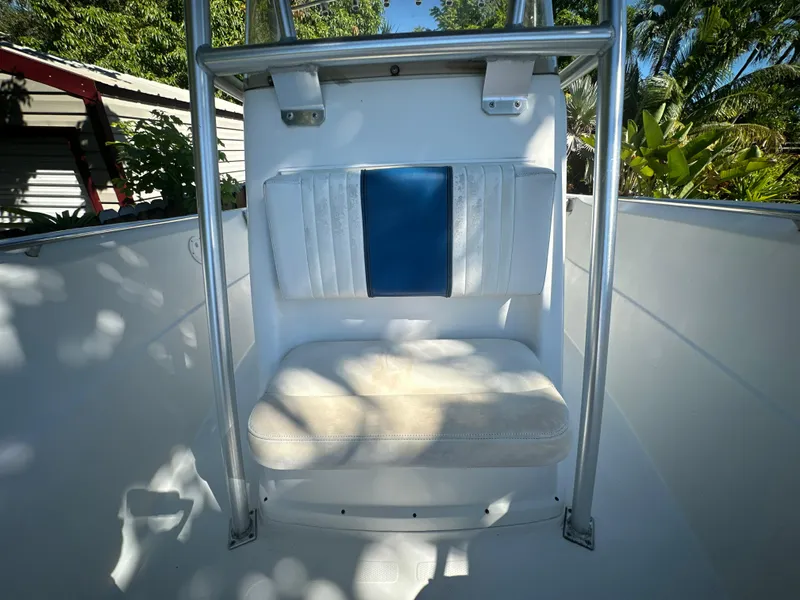 Slide: The Image of 2005 Sailfish 2360 CC boat seat with blue and white upholstery, surrounded by greenery. - 21