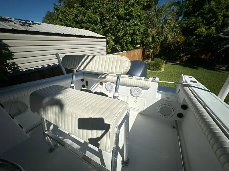 Slide: The Image of 2005 Sailfish 2360 CC boat interior with seating, set in a sunny backyard. - 22