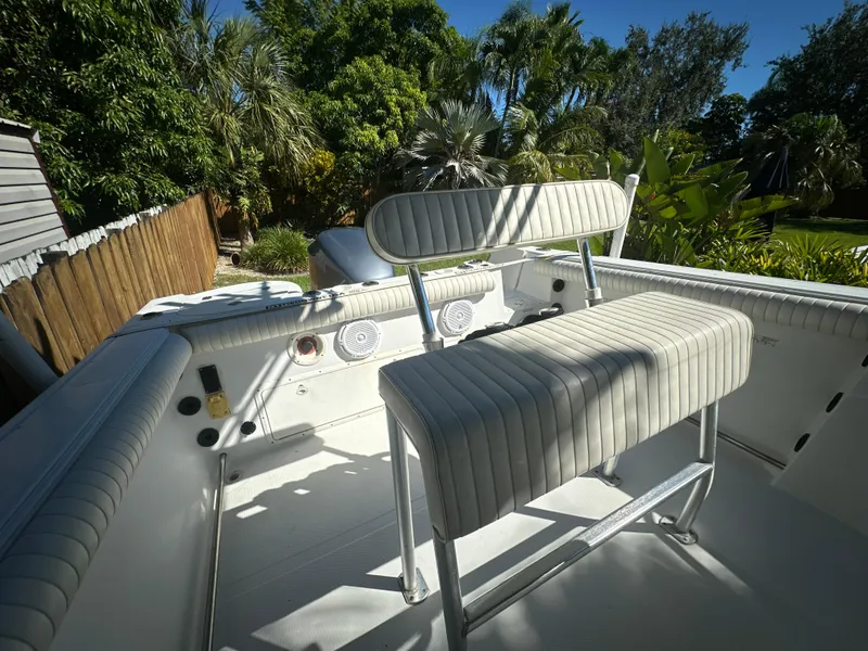 Slide: The Image of 2005 Sailfish 2360 CC boat interior with seating, surrounded by lush greenery. - 23