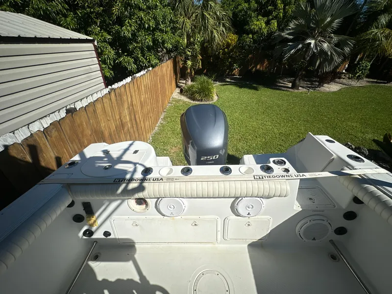 Slide: The Image of 2005 Sailfish 2360 CC boat with outboard motor in a sunny backyard setting. - 8