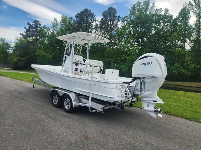 Slide: The Image of 2025 BlackJack 256 Bay boat with Yamaha engine on a trailer, parked on a road. - 2