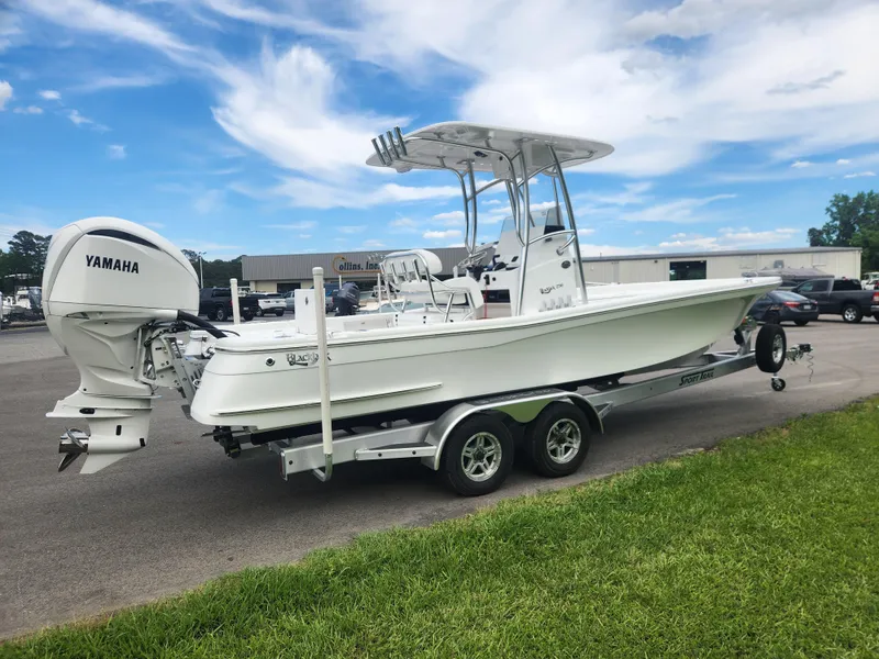 Slide: The Image of 2025 BlackJack 256 Bay boat with Yamaha engine on trailer, parked outdoors. - 5