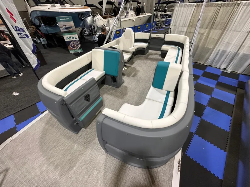 Slide: The Image of 2025 Avalon Aura 21' boat interior with white and teal seating, showcased at a boat exhibition. - 11