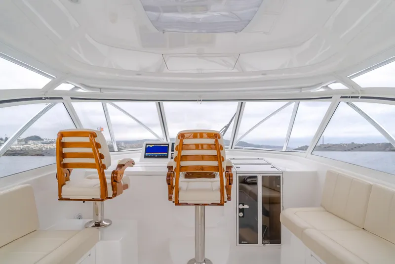 Slide: The Image of 2022 Viking 38 Open Billfish helm with wooden chairs and panoramic windows. - 12