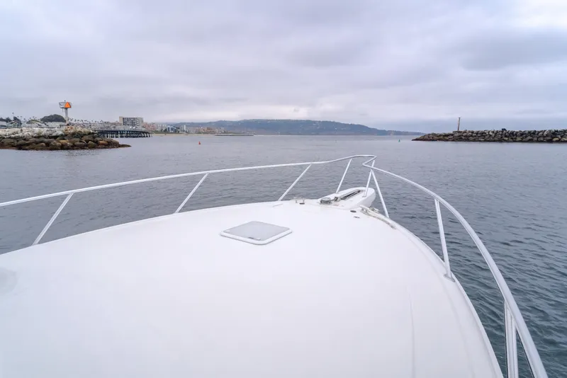 Slide: The Image of Bow view of 2022 Viking 38 Open Billfish navigating calm waters near a rocky shoreline. - 29