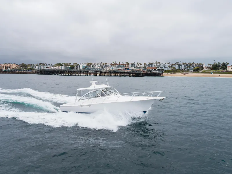 Slide: The Image of 2022 Viking 38 Open Billfish cruising near a coastal pier under cloudy skies. - 33
