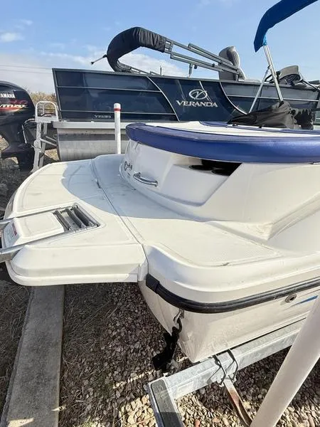 Slide: The Image of 2012 Sea Ray 185 Sport boat on trailer, rear view, with Veranda pontoon in background. - 6