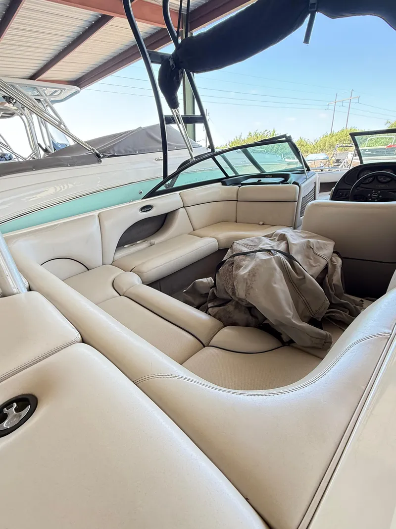 Slide: The Image of Interior of a 2002 Malibu 21 LSV boat with beige seating under a canopy. - 10