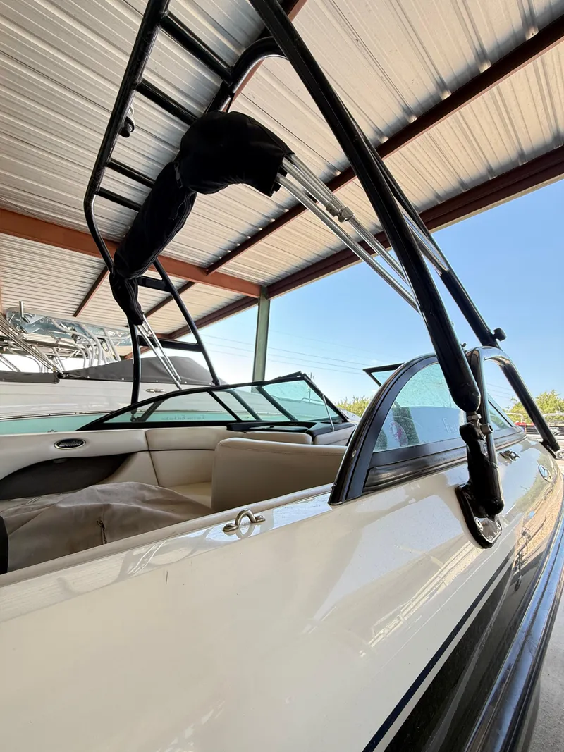 Slide: The Image of 2002 Malibu 21 LSV boat under a metal canopy, showcasing interior and wakeboard tower. - 12