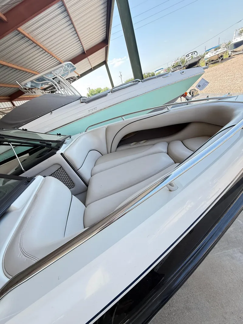 Slide: The Image of 2002 Malibu 21 LSV boat interior with white seating, under a metal roof. - 13