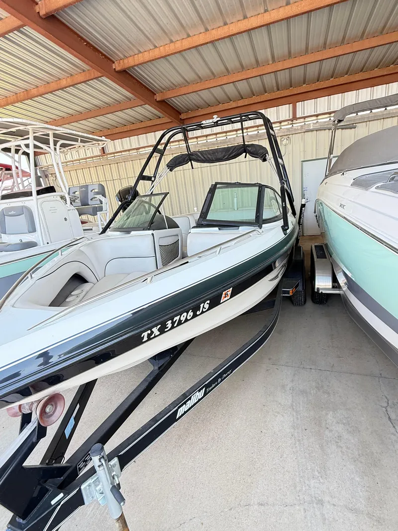 Slide: The Image of 2002 Malibu 21 LSV boat in storage, black and white exterior, on a trailer. - 14