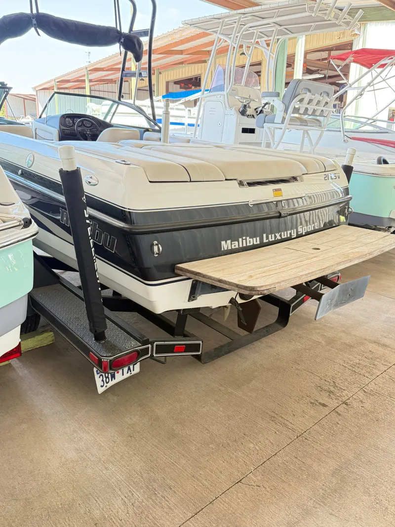 Slide: The Image of 2002 Malibu 21 LSV boat in storage, featuring a swim platform and luxury sport design. - 15