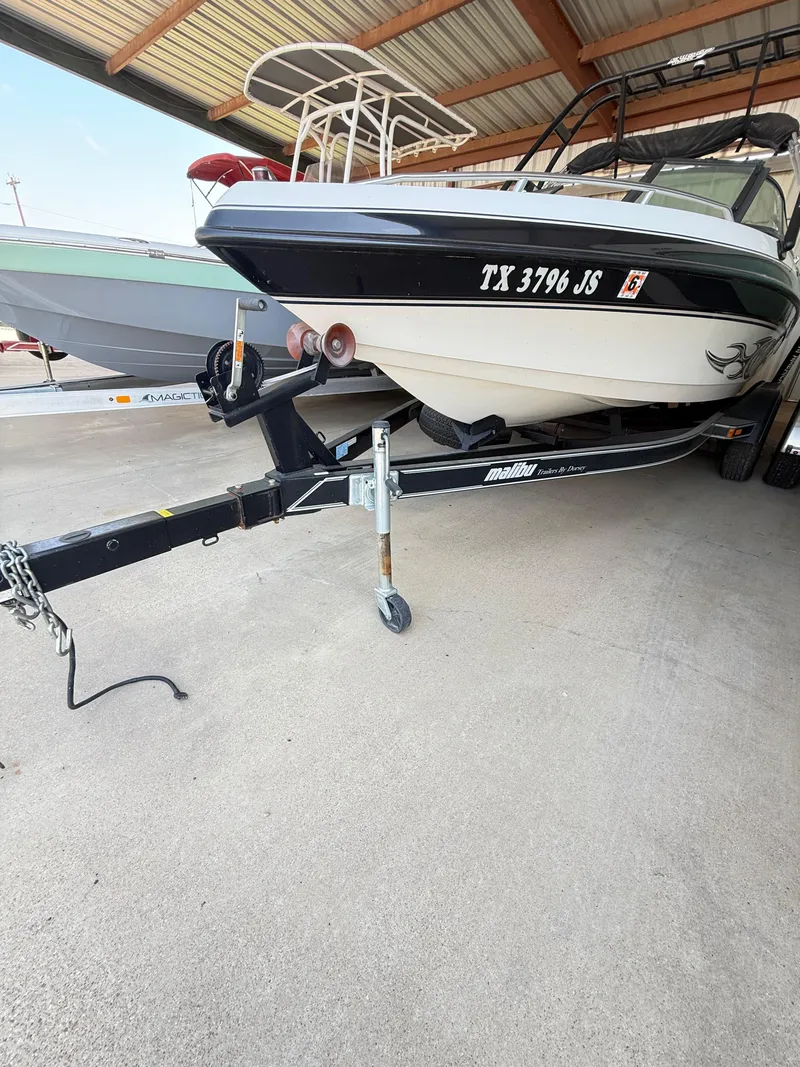Slide: The Image of 2002 Malibu 21 LSV boat on trailer under a metal roof. - 9