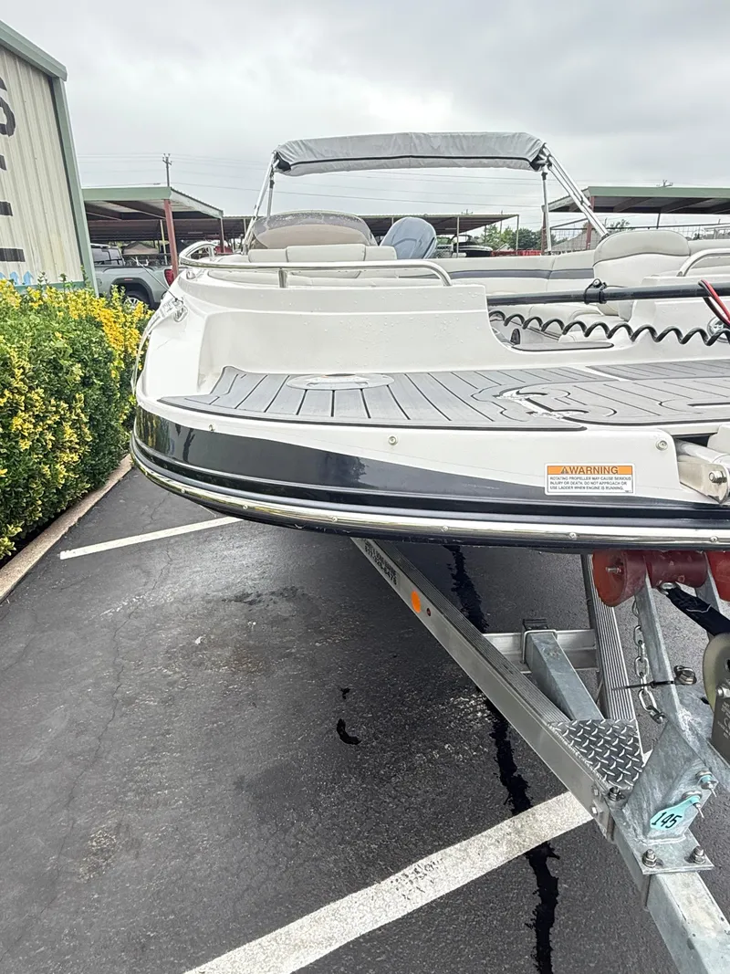 Slide: The Image of 2021 Starcraft MDX191 boat on trailer, parked outdoors near greenery. - 12