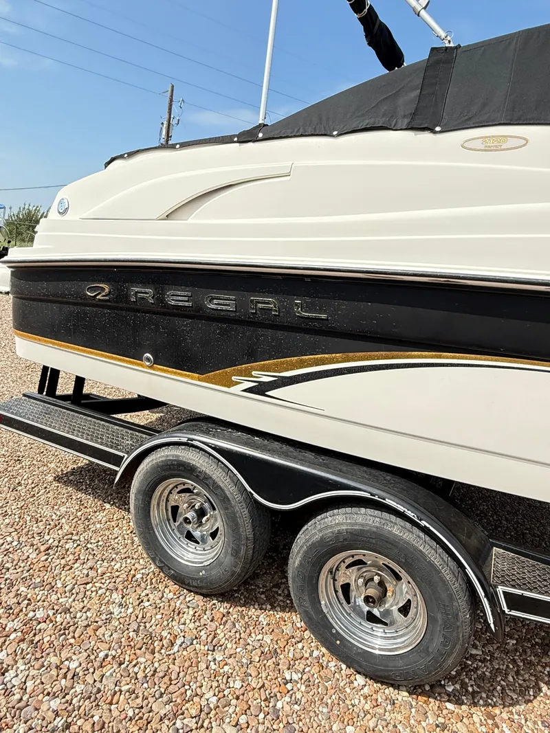 Slide: The Image of 2002 Regal 2120 Destiny boat on trailer, side view with black and gold accents. - 3