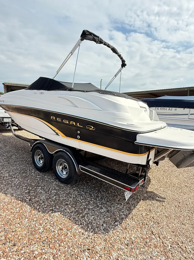 Slide: The Image of 2002 Regal 2120 Destiny boat on trailer, parked outdoors under cloudy sky. - 6