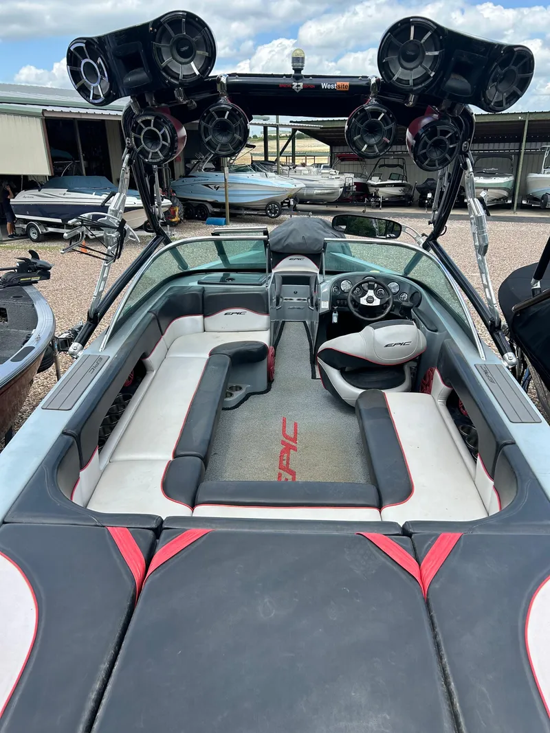 Slide: The Image of 2012 Epic 23V boat interior with seating and audio system, docked in a marina. - 10