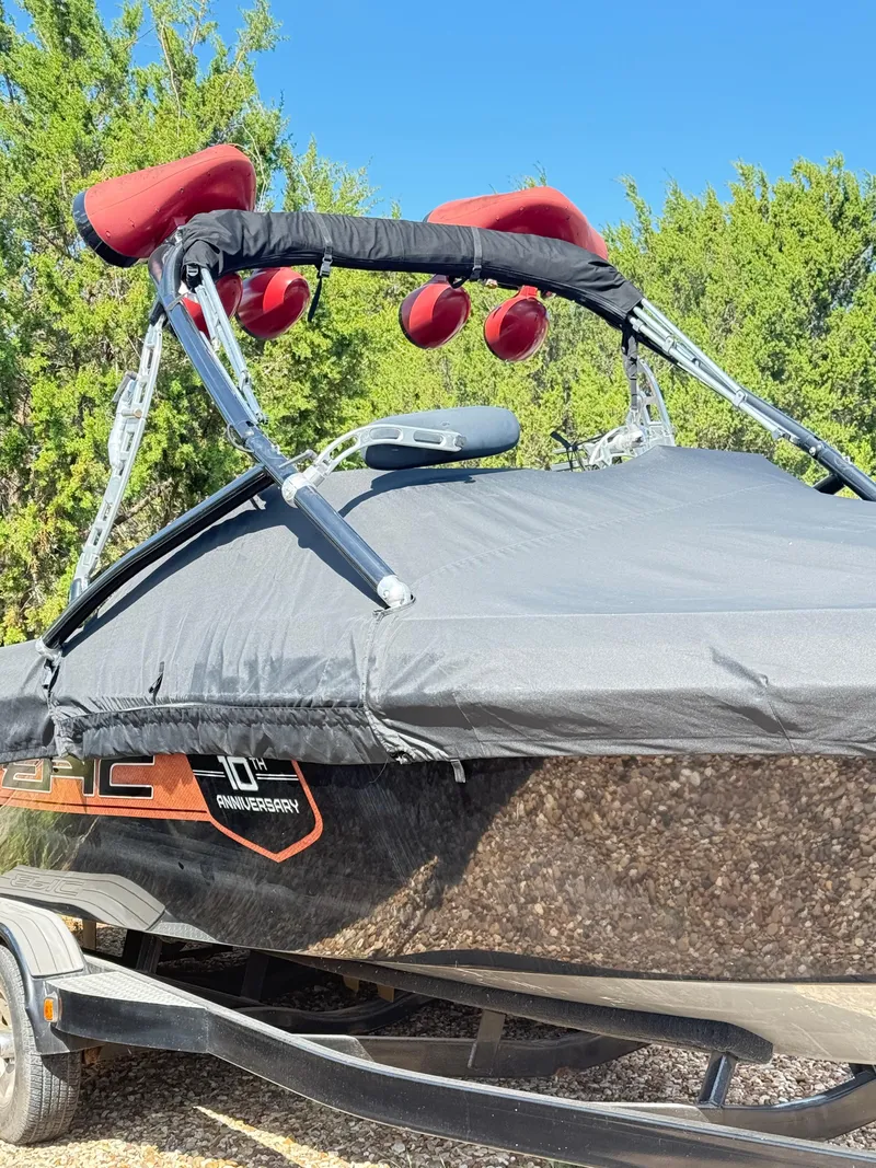 Slide: The Image of 2012 Epic 23V boat with cover and red speakers, parked on trailer. - 2