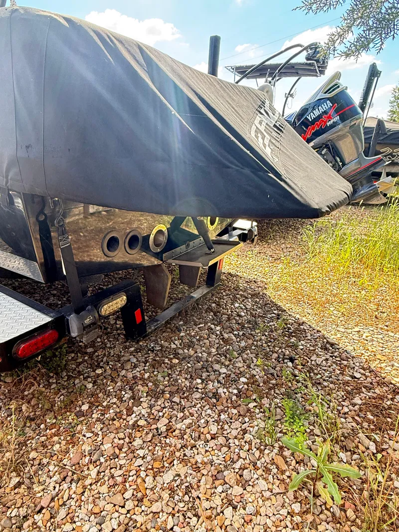 Slide: The Image of Covered 2012 Epic 23V boat on trailer, parked on gravel with sunlight. - 7