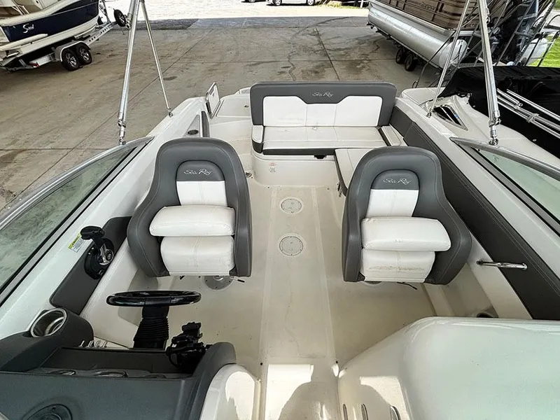 Slide: The Image of 2011 Sea Ray 240 Sundeck interior with white seating and steering wheel. - 16