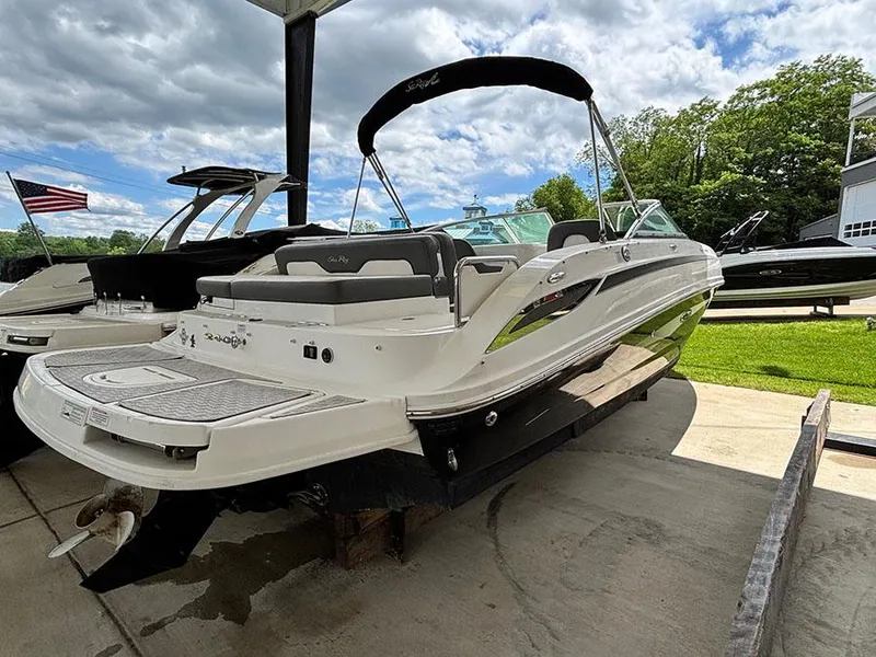 Slide: The Image of 2011 Sea Ray 240 Sundeck boat on trailer, outdoor setting, partly cloudy sky. - 2
