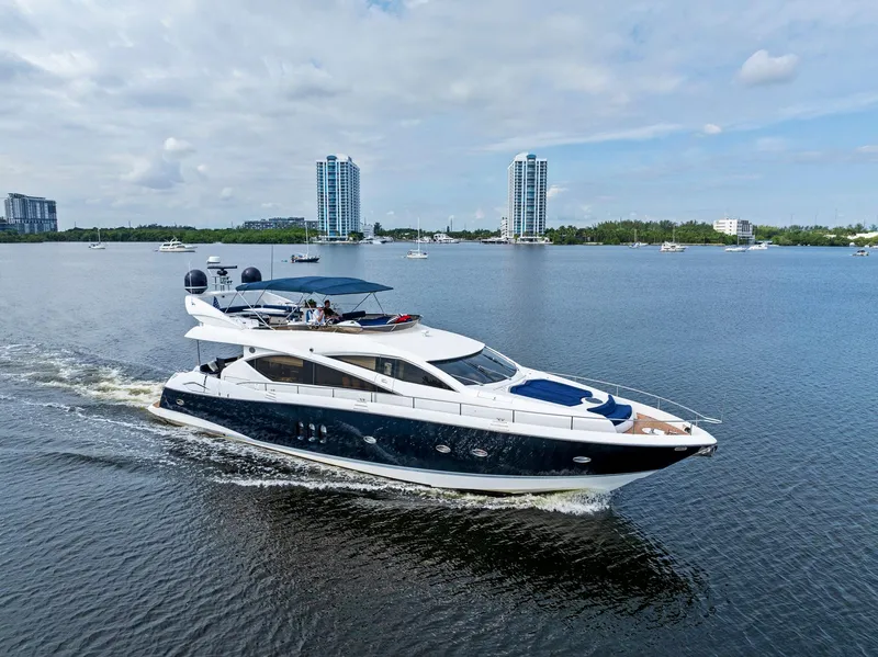 Slide: The Image of 2006 Sunseeker 75 Yacht cruising on a calm waterway with cityscape background. - 14