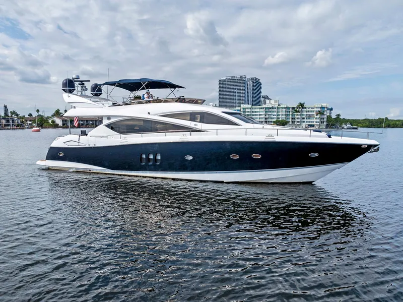 Slide: The Image of 2006 Sunseeker 75 Yacht on calm water, with modern buildings in the background. - 2