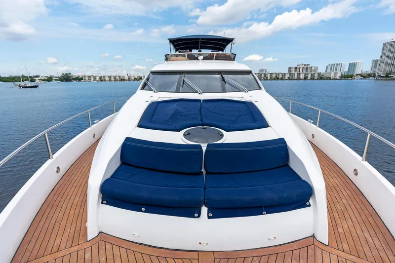Slide: The Image of 2006 Sunseeker 75 Yacht with blue sunbeds on deck, docked in a scenic marina. - 34