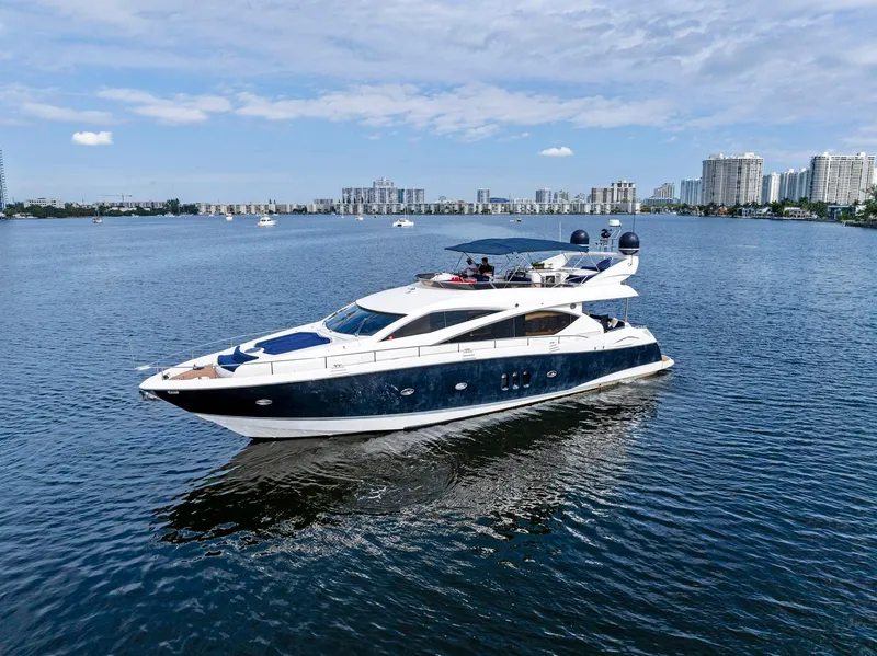 Slide: The Image of 2006 Sunseeker 75 Yacht cruising on a calm, scenic waterway with city skyline backdrop. - 9