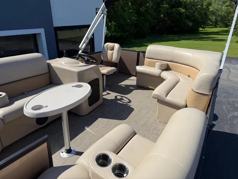 Slide: The Image of 2019 Bentley Pontoons 180 CRUISE interior with beige seating and table, set against a green landscape. - 12