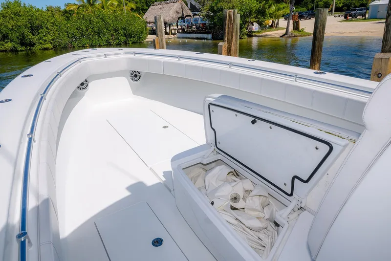 Slide: The Image of 2022 Contender 39 ST boat interior with open storage compartment, docked by lush greenery. - 12