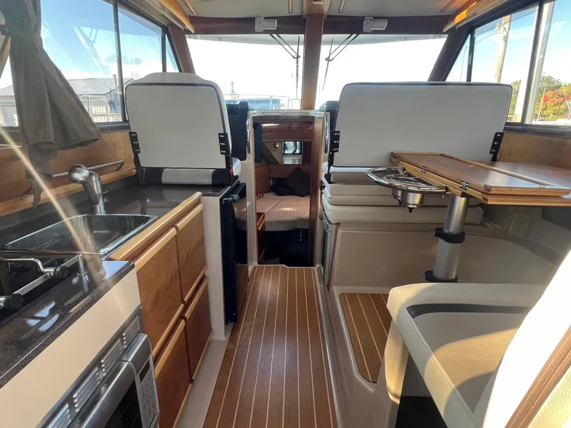 Slide: The Image of Interior of a 2016 Cutwater C28 boat featuring a compact kitchen and seating area. - 19
