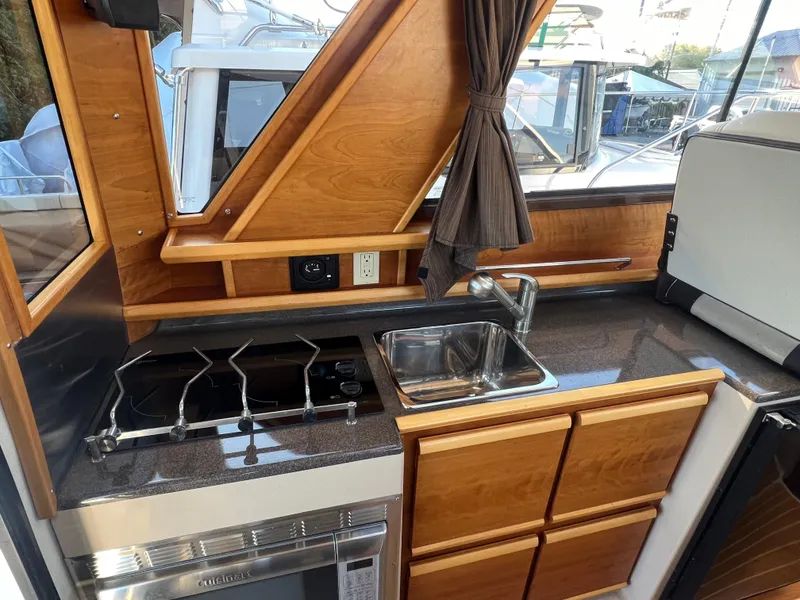 Slide: The Image of 2016 Cutwater C28 boat kitchen with stove, sink, and wooden cabinetry. - 34
